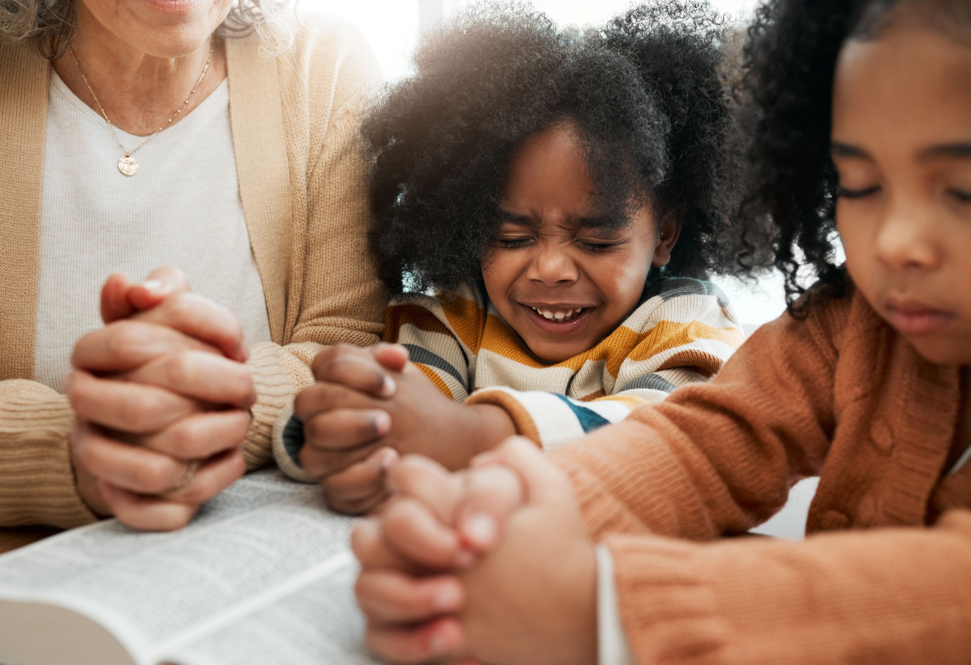 Bible, prayer or hands of grandmother with kids or siblings for worship, support or hope in Christianity. Children education, praying or old woman studying, reading book or learning God in religion
